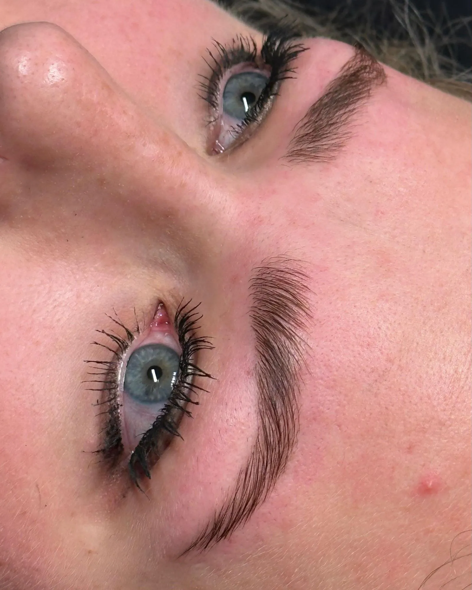 Seitliche Nahaufnahme mit definiert gestylten Augenbrauen und betonten Wimpern.